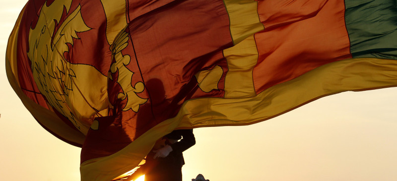Air force officer holds Sri Lanka's national flag as the sun sets at Galle Face Green in Colombo